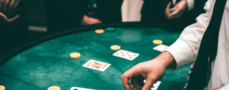 Bàn Blackjack nỉ xanh với lá Át và lá K tạo thành bài 21 tự nhiên cùng vài chồng phỉnh cược casino nhiều màu